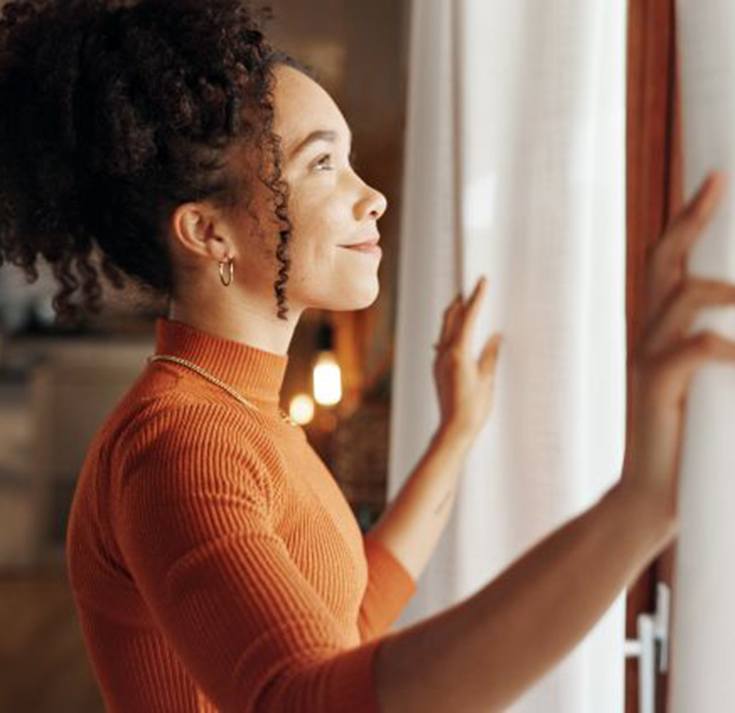 Woman opening her curtains in the morning