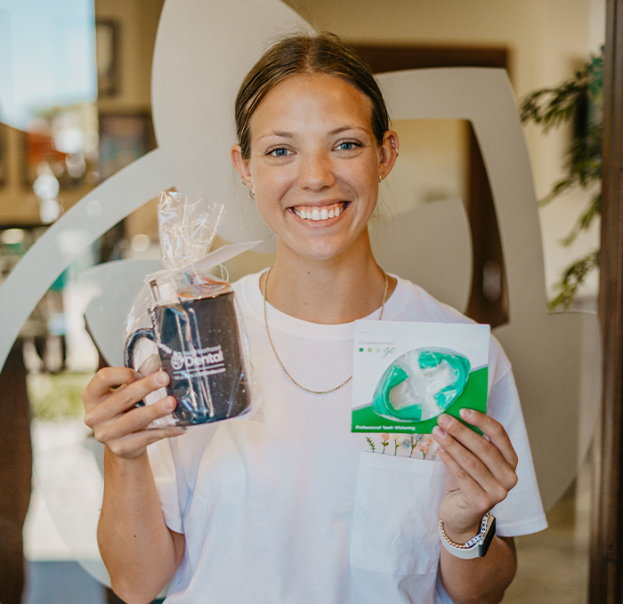 Smiling woman holding coffee mug and teeth whitening trays