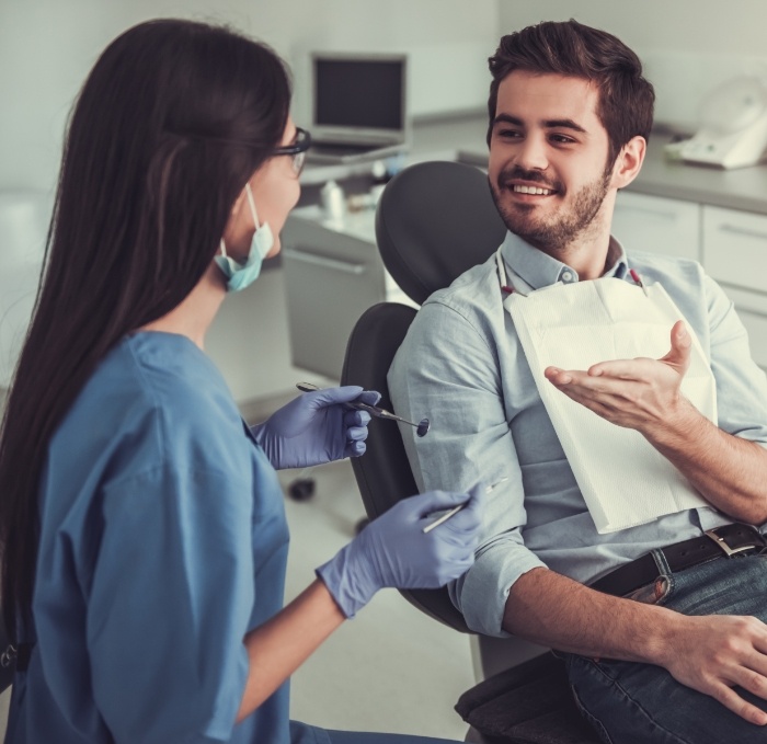 Young man with short beard talking to cosmetic dentist