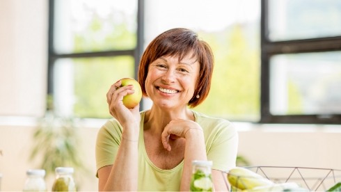 Smiling woman holding a green apple