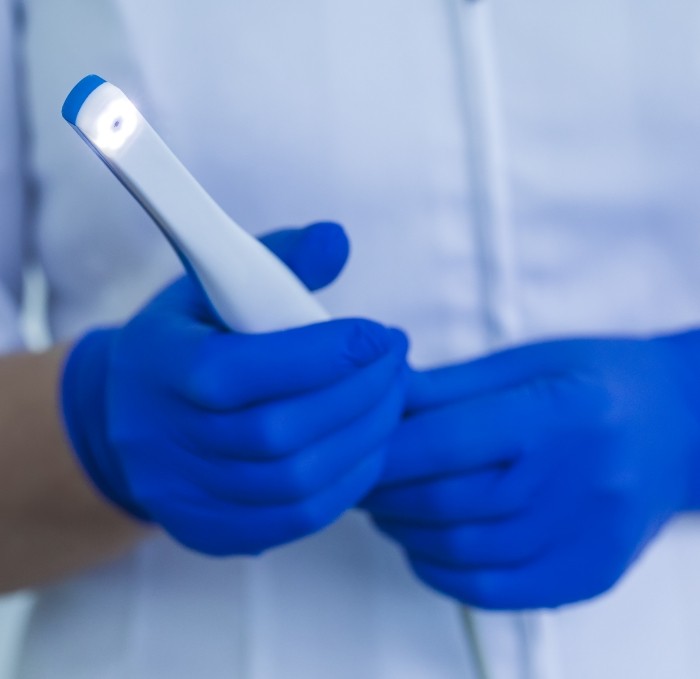 Two gloved hands holding a thin white intraoral camera