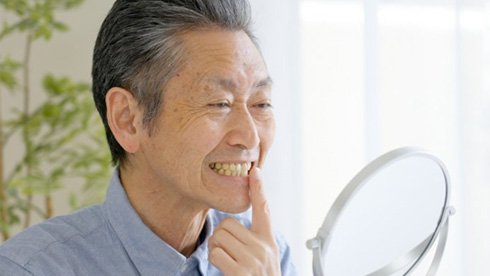 a man checking his dentures with a mirror