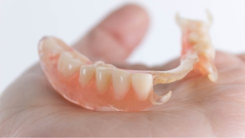 Person holding a partial denture in their hand