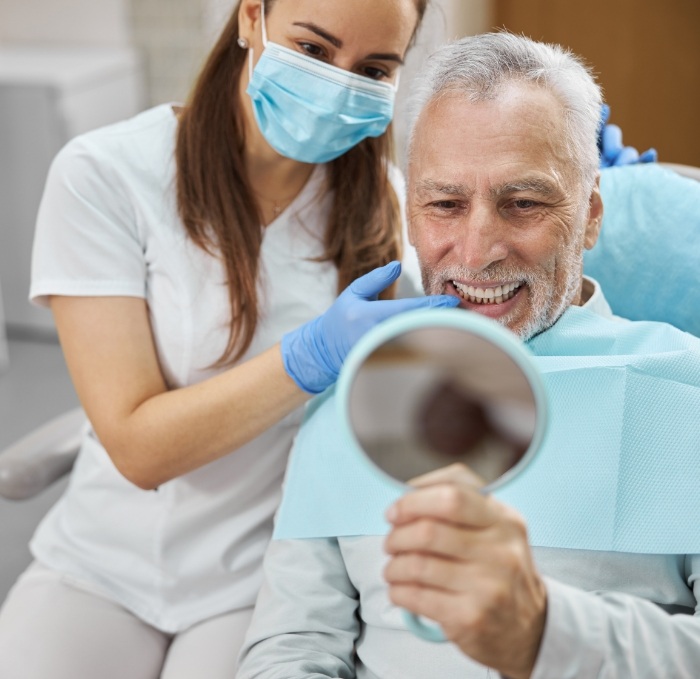 Dental team member showing a patient his smile in mirror