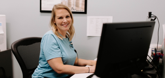 Smiling team member at Neighborhood Dental Brandon sitting at desk on computer