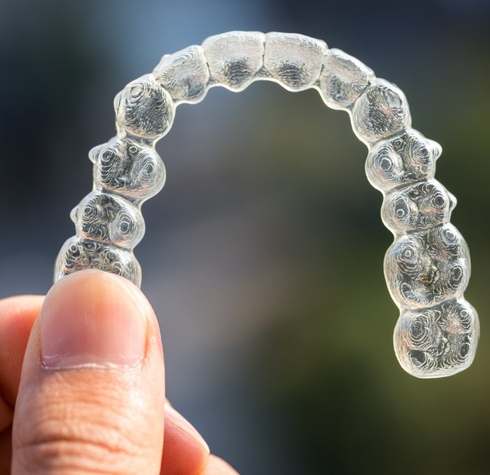 Hand holding Invisalign clear aligner in Brandon