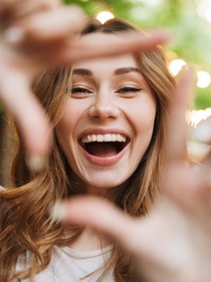 Woman smiling wide and making a box with her fingers
