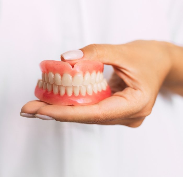 Hand holding a set of full dentures