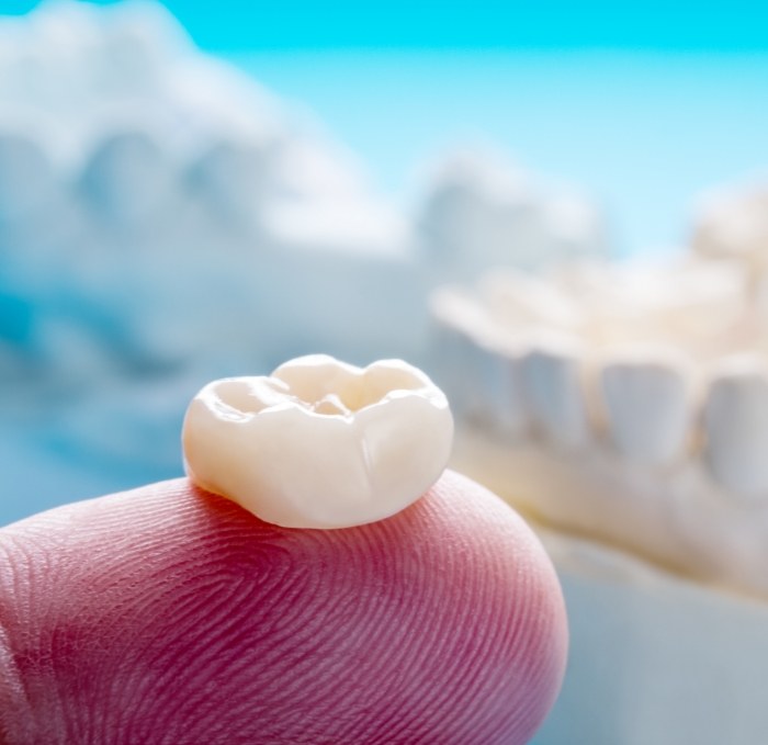 Person holding a dental crown on their finger