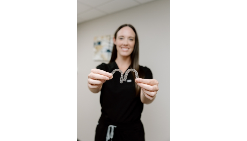 Dr. Mauri Heesch holding Invisalign clear aligners at Neighborhood Dental in Brandon, SD
