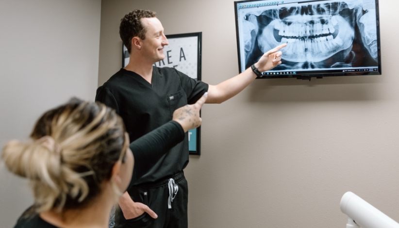 Dentist Dr. Alex Woods explaining a dental X-ray to a patient during a checkup