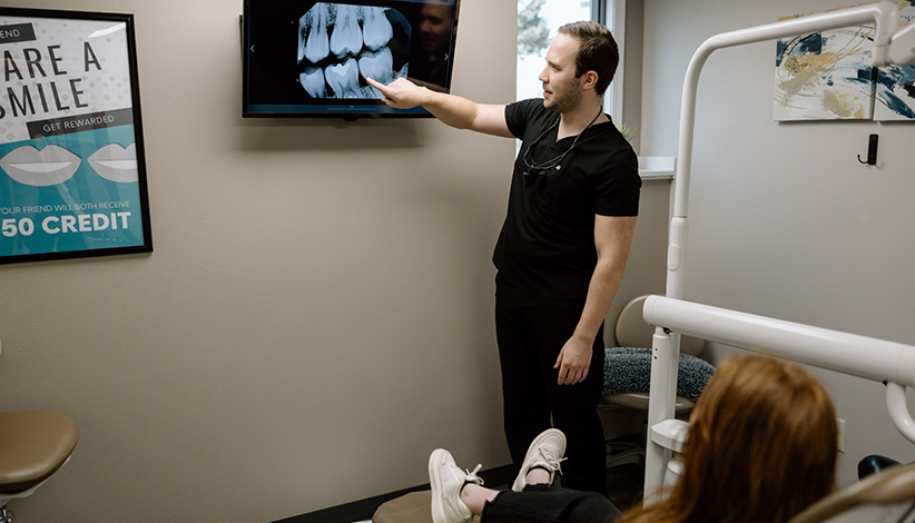 Dentist Dr. Andrew Schuiteman explaining a dental X-ray to a patient during a checkup