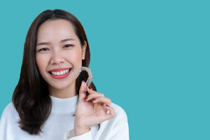 a patient smiling and holding her Invisalign aligner