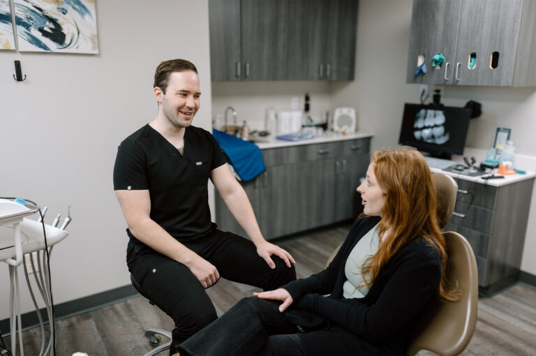 A dentist talking to woman patient in dental chair at Neighborhood Dental Brandon in South Dakota.