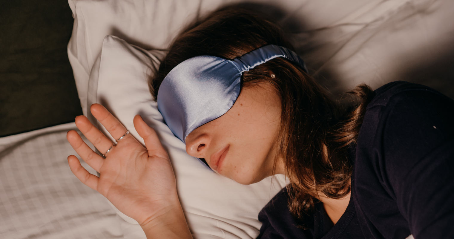 A woman peacefully sleeping with a blue eye mask.